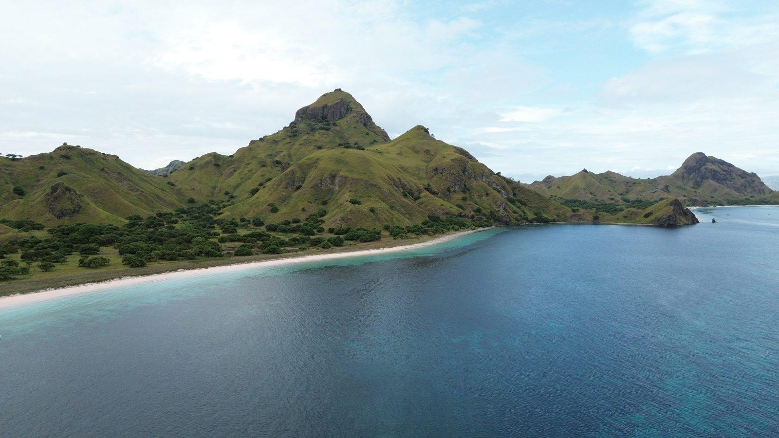 Padar – Aerial jagged green ridge, curved white beach (Real photo from a KEXI trip)